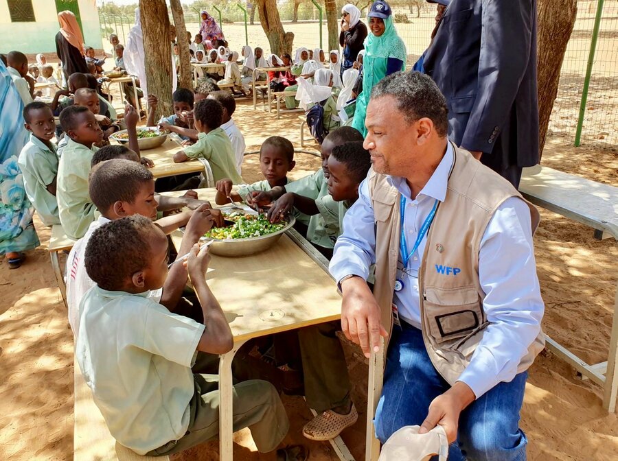 WFP's Hameed Nuru with students in Darfur, Sudan, as they enjoyed a meal cooked with ingredients from their school garden. The visit took place when Nuru was WFP Sudan Country Director. Photo: WFP Sudan &nbsp;